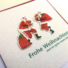 Weihnachtskarte zwei Weihnachtsmänner mit Geschenke-Säcken und viel Glimmer
